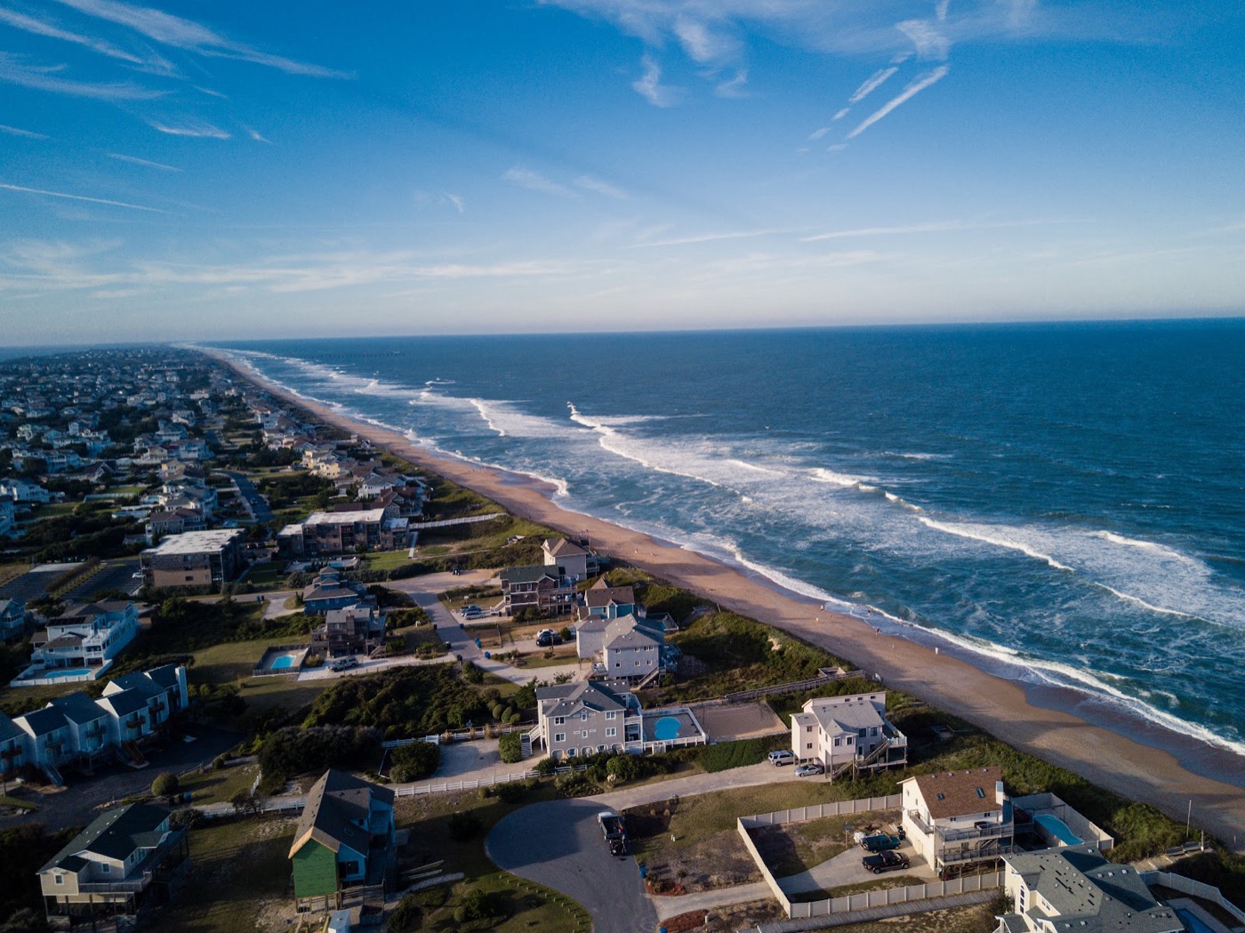 Aerial view of beach houses along a sweeping ocean coastline