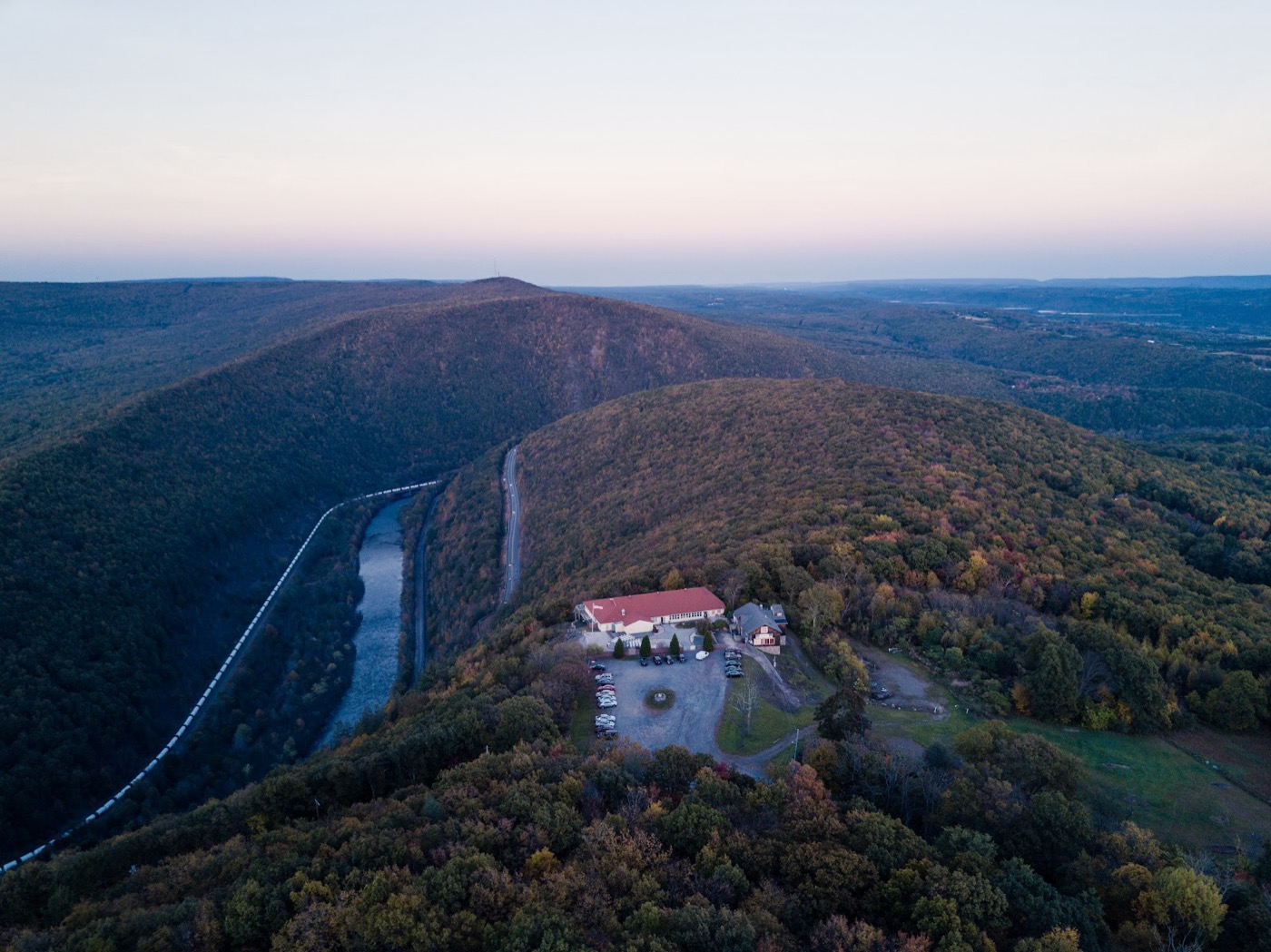 Aerial view of a river winding through a forested mountain gorge at dusk